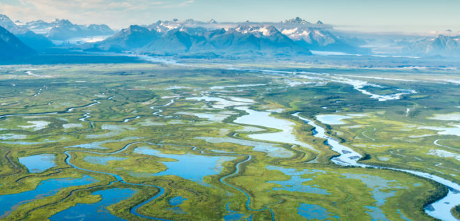 Aerial view of the Copper River Delta with glacier and mountains in the background